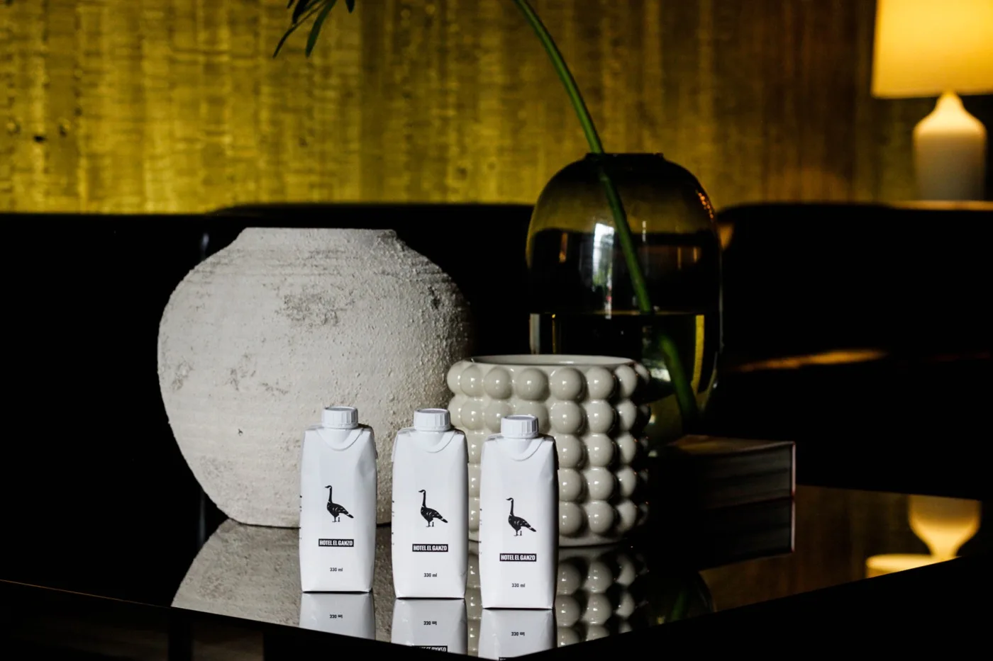 Tres envases impresos con la marca de Hotel El Ganzo, sobre una mesa del hotel