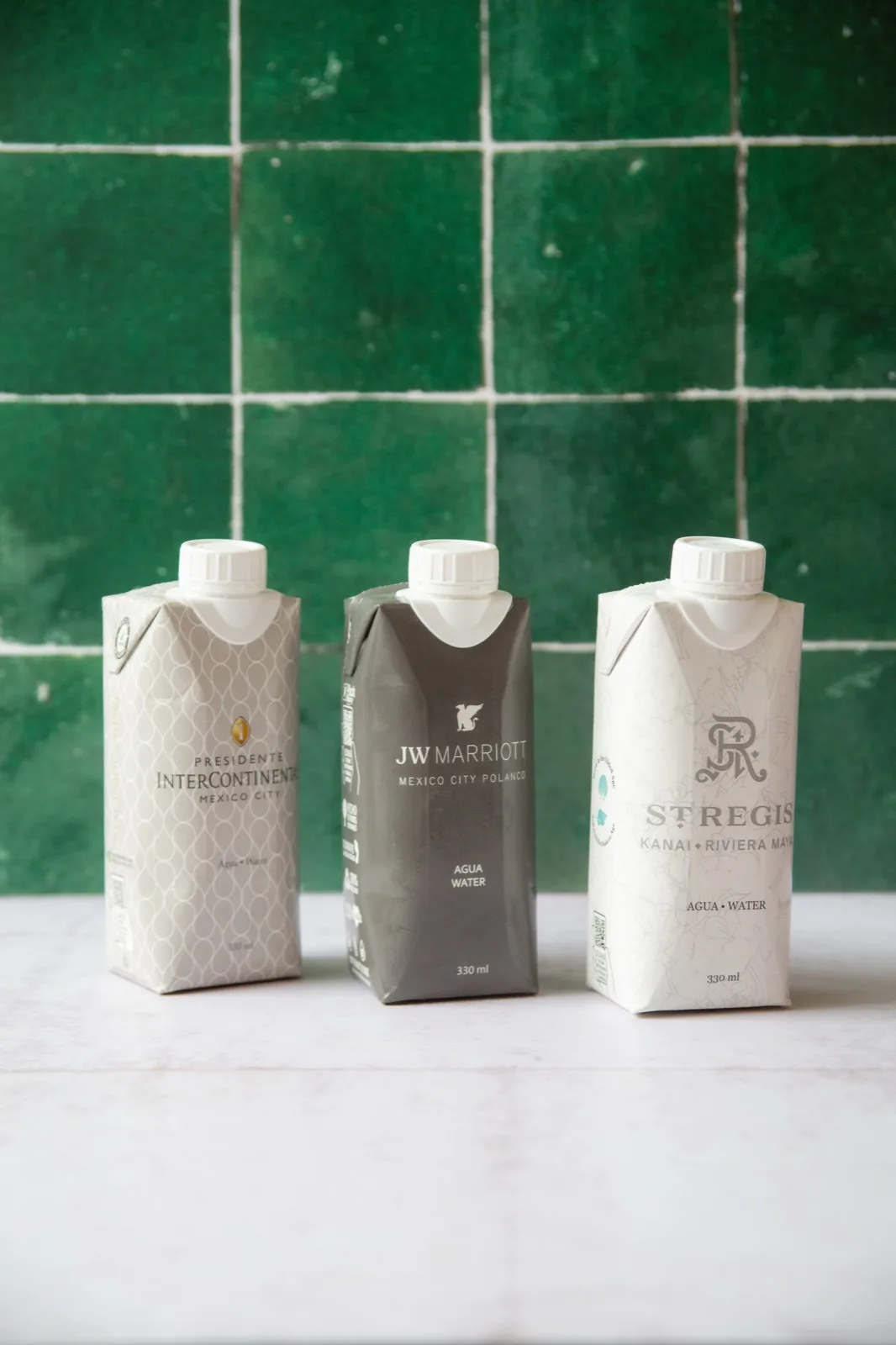 Tres envases de Water Matters impresos con las marcas de Presidente InterContinental, JW Marriott y St. Regis Kanai